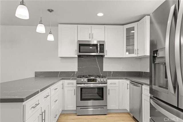 kitchen featuring appliances with stainless steel finishes, pendant lighting, backsplash, and white cabinets