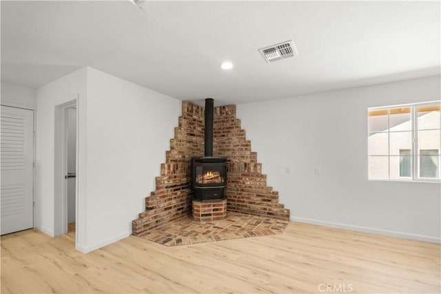 unfurnished living room featuring a wood stove and light hardwood / wood-style flooring