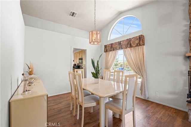 dining room with high vaulted ceiling, dark wood-type flooring, and a chandelier