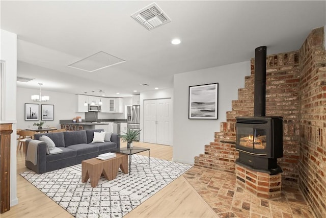 living room with brick wall, an inviting chandelier, and a wood stove