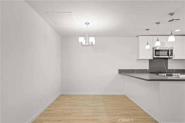 kitchen featuring tasteful backsplash, light hardwood / wood-style floors, an inviting chandelier, hanging light fixtures, and white cabinets