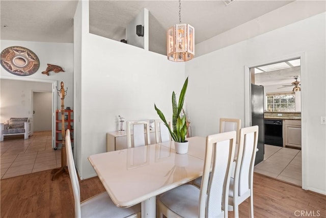 dining space with ceiling fan with notable chandelier and light hardwood / wood-style flooring