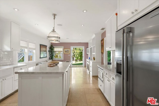 kitchen with stainless steel appliances, decorative backsplash, white cabinets, and a center island