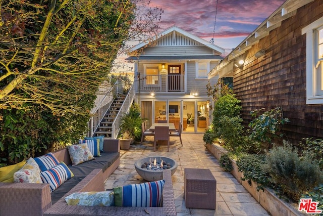 patio terrace at dusk featuring an outdoor living space and a balcony