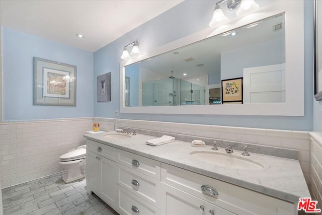 bathroom featuring tile patterned floors, vanity, tile walls, toilet, and a shower with shower door