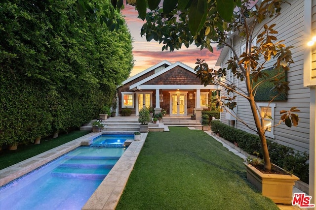 back house at dusk with a lawn