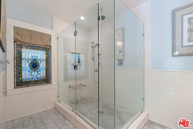 bathroom featuring tile walls and a shower with door