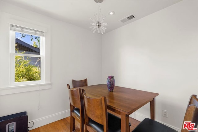 dining space with light hardwood / wood-style floors and a notable chandelier