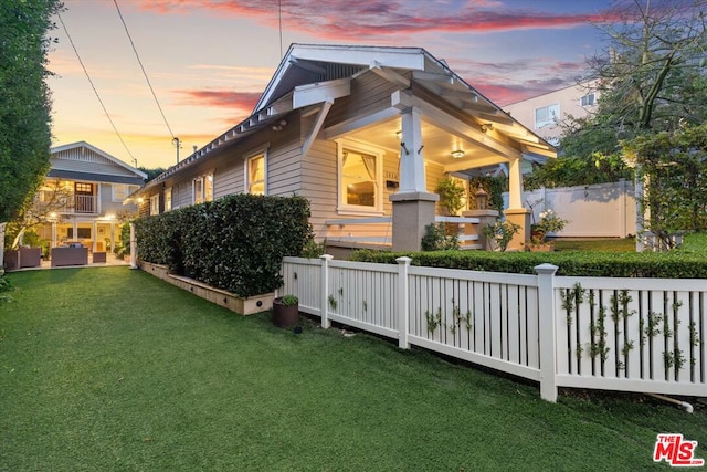 property exterior at dusk featuring a lawn