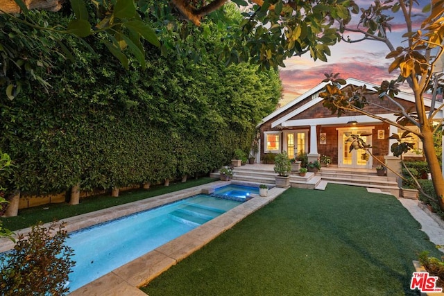 pool at dusk featuring an in ground hot tub and french doors