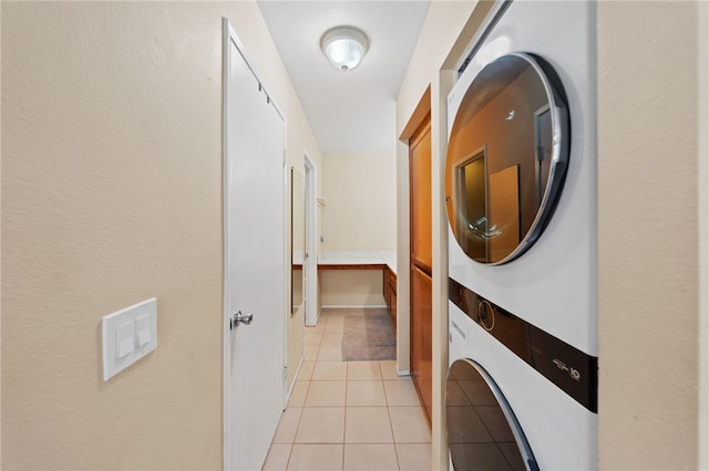 laundry area with light tile patterned floors and stacked washer and dryer