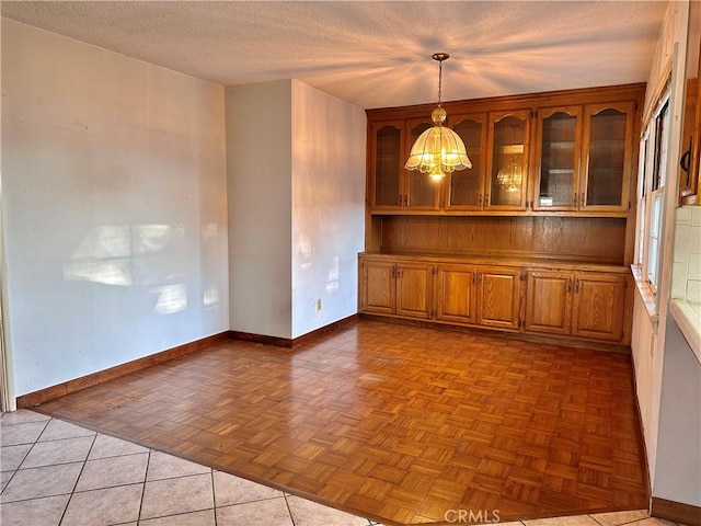 unfurnished dining area with a notable chandelier, light tile patterned floors, and a textured ceiling