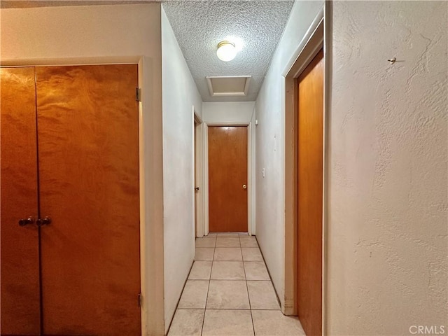 corridor with light tile patterned floors and a textured ceiling