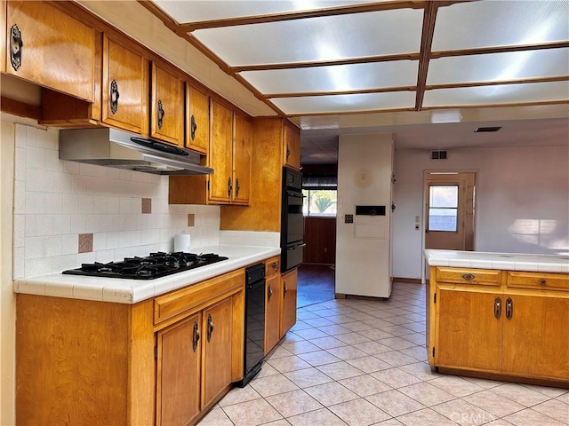 kitchen with tile countertops, white gas stovetop, decorative backsplash, black oven, and light tile patterned flooring