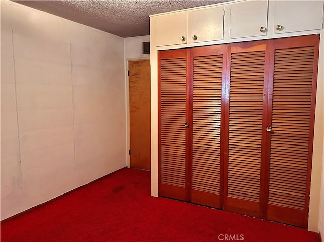 unfurnished bedroom with dark carpet and a textured ceiling