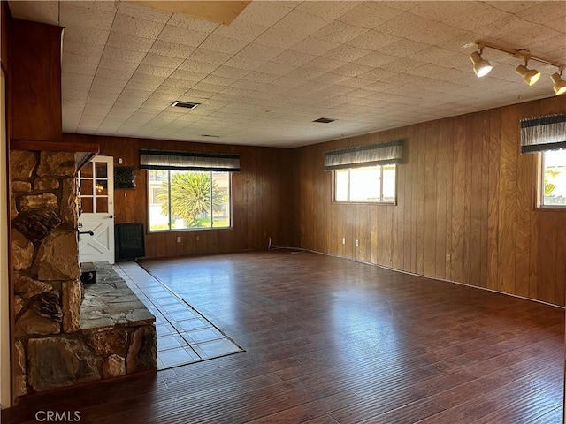 unfurnished room with wood walls, hardwood / wood-style floors, a healthy amount of sunlight, and track lighting