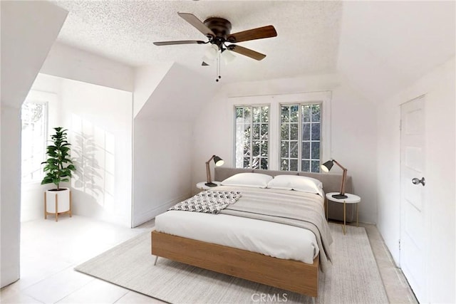 bedroom with vaulted ceiling, ceiling fan, and a textured ceiling