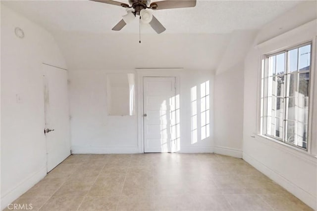 tiled spare room with vaulted ceiling and ceiling fan