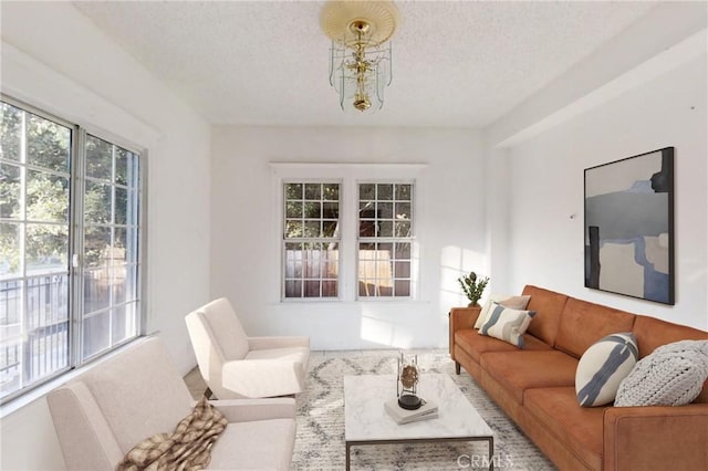 living room with a textured ceiling, an inviting chandelier, and a healthy amount of sunlight