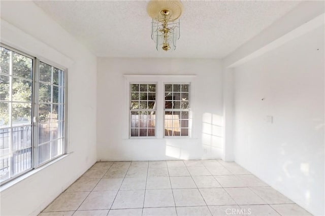 unfurnished dining area with light tile patterned floors, a textured ceiling, and a notable chandelier