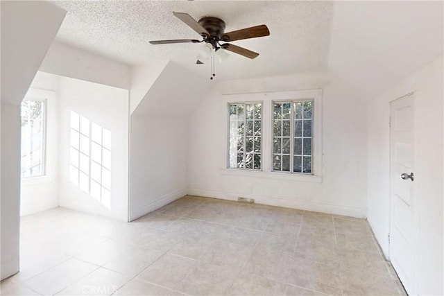 bonus room with lofted ceiling, ceiling fan, light tile patterned floors, and a textured ceiling