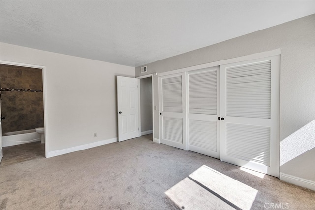 unfurnished bedroom featuring ensuite bath and light colored carpet