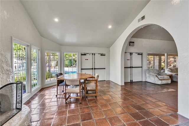 dining space featuring a wealth of natural light, a textured ceiling, and high vaulted ceiling