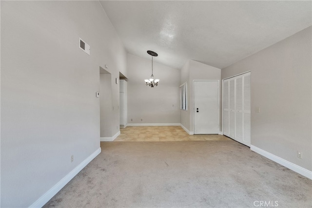 empty room featuring an inviting chandelier, lofted ceiling, and light colored carpet