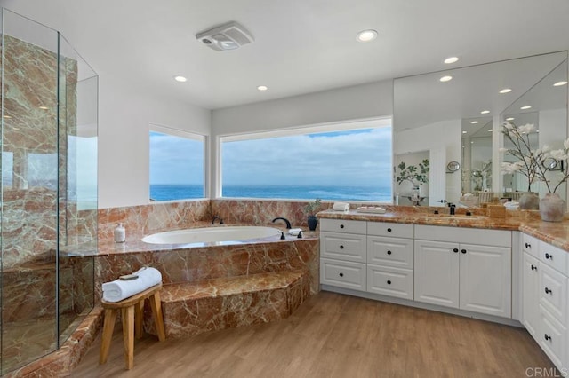 bathroom with vanity, hardwood / wood-style floors, tiled tub, and a water view