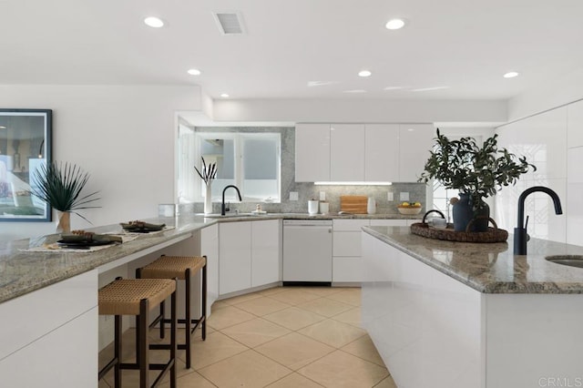 kitchen featuring white cabinetry, dishwasher, light stone countertops, and sink