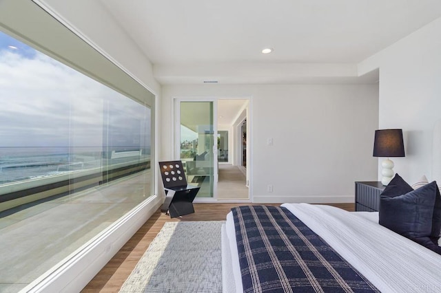 bedroom with wood-type flooring and a water view