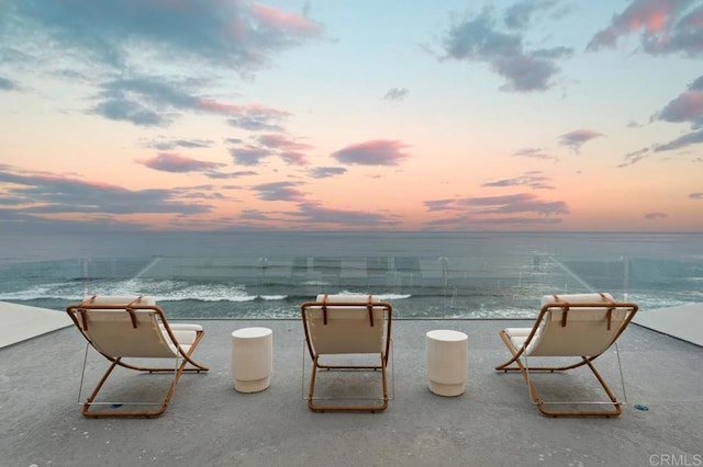 patio terrace at dusk featuring a water view