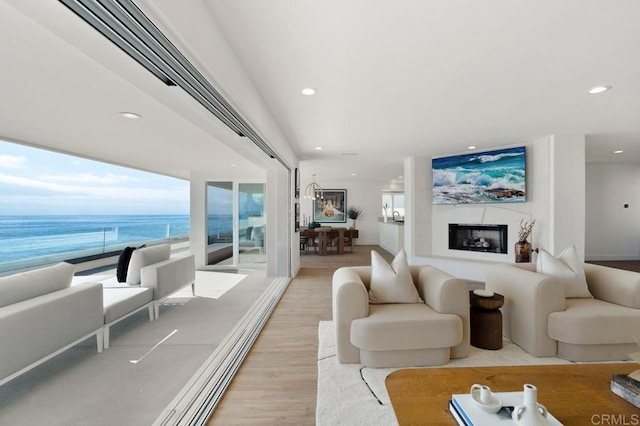 living room with a view of the beach, a water view, and light wood-type flooring