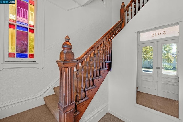 stairs featuring french doors and carpet flooring