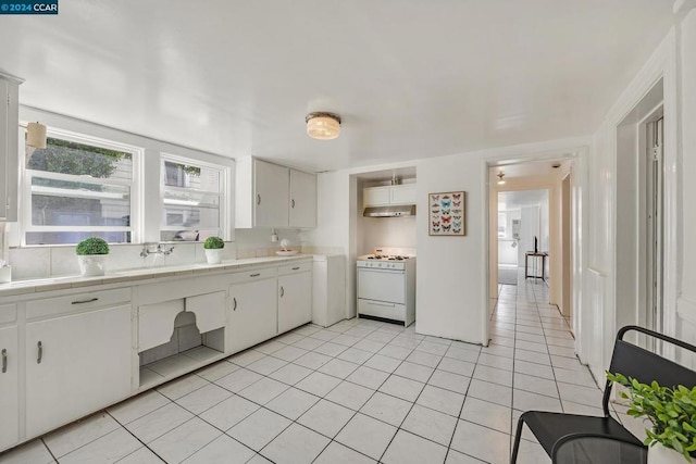 kitchen with white cabinetry, white gas range oven, light tile patterned flooring, and sink