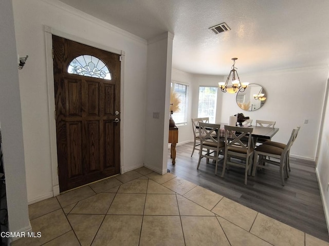 entryway featuring hardwood / wood-style floors, a notable chandelier, crown molding, and a textured ceiling