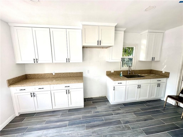 kitchen featuring white cabinets, stone countertops, and sink