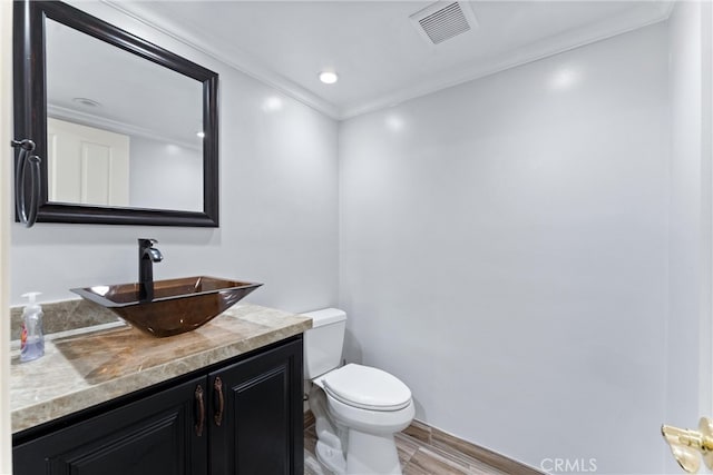 bathroom with crown molding, vanity, toilet, and hardwood / wood-style floors