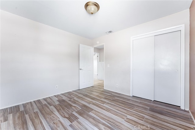 unfurnished bedroom featuring light wood-type flooring and a closet