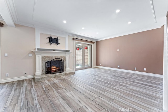 unfurnished living room featuring light wood-type flooring, a premium fireplace, and crown molding