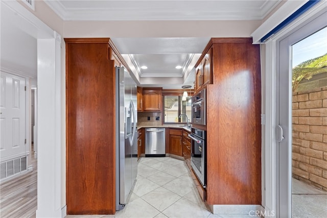 kitchen with sink, light tile patterned floors, brick wall, appliances with stainless steel finishes, and crown molding