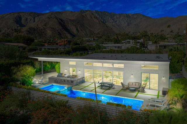 view of swimming pool featuring an outdoor kitchen, an in ground hot tub, a mountain view, outdoor lounge area, and a patio