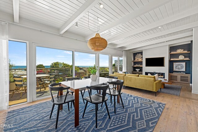 dining area with built in shelves, beamed ceiling, hardwood / wood-style flooring, and a healthy amount of sunlight