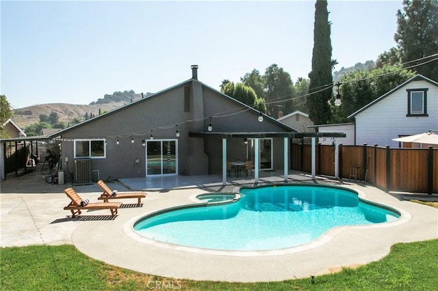 exterior space featuring an in ground hot tub, a mountain view, and a patio area