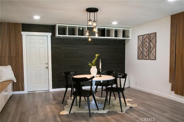 dining space with dark hardwood / wood-style floors and wood walls