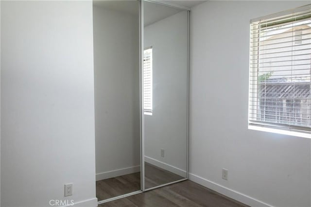 unfurnished bedroom with dark hardwood / wood-style flooring and a closet