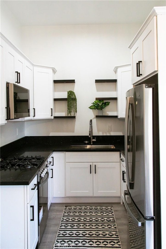 kitchen with dark hardwood / wood-style flooring, stainless steel appliances, white cabinetry, and sink