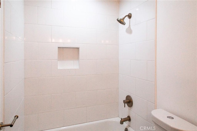 bathroom featuring tiled shower / bath combo and toilet