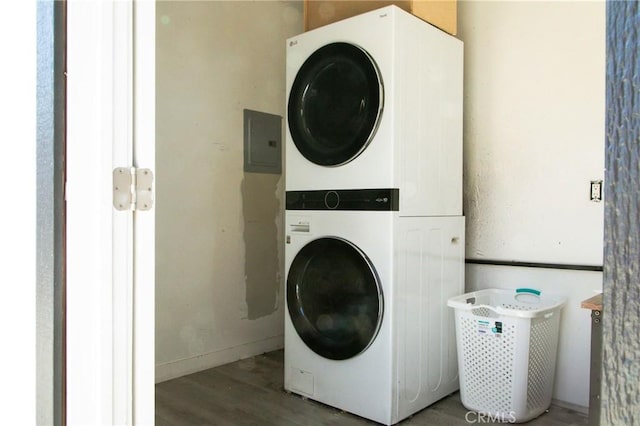 laundry area with electric panel, hardwood / wood-style floors, and stacked washer / drying machine