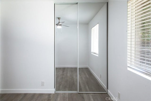 unfurnished bedroom featuring dark hardwood / wood-style floors, ceiling fan, and a closet